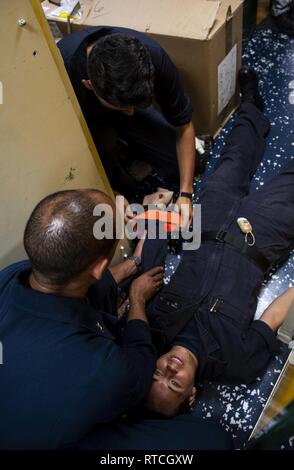 GULF OF THAILAND (Feb. 19, 2019) – Logistics Specialist 1st Class Leonexon Rodriguez, left, from Dominican Republic, and Logistics Specialist Seaman Angel Lopez, top, from Los Angeles, treat a simulated patient, Seaman Bethany York, from Laurel Hill, N.C., during a medical training team evolution aboard the amphibious transport dock ship USS Green Bay (LPD 20). Green Bay, part of the Wasp Amphibious Ready Group, with embarked 31st Marine Expeditionary Unit (MEU), is in Thailand to participate in Exercise Cobra Gold 2019. Cobra Gold is a multinational exercise co-sponsored by Thailand and the U Stock Photo