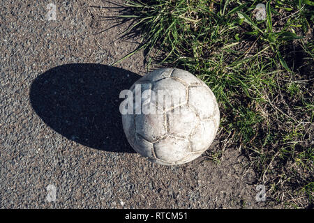 Aged white soccer ball on asphalt road Stock Photo