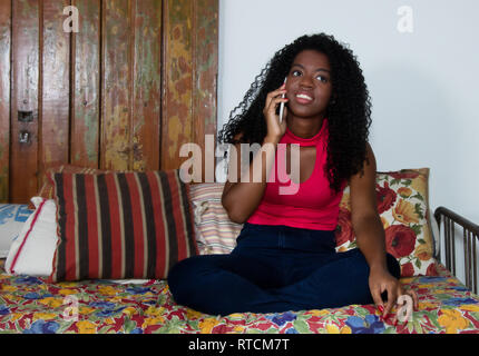 African american woman talking with other woman at cellphone on couch at home Stock Photo