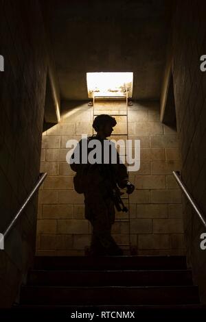 U.S. Marine Corps Cpl. Donald Darnell, rifleman with Charlie Company, 1st Battalion, 7th Marine Regiment, pauses before exiting a building for a Military Operations on Urban Terrain operation during an Advanced Infantry Marine Course (AIMC) field leadership evaluation at Schofield Barracks, Feb. 14, 2019. AIMC is intermediate training designed to enhance and test the Marine's skills and leadership abilities as squad leaders in a rifle platoon. Stock Photo