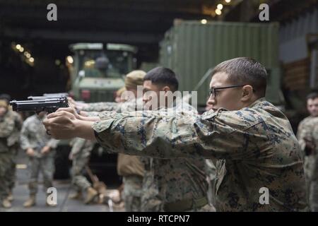 Lance Cpl. Andrew Foss, a rifleman with Alpha Company, Battalion Landing Team, 1st Battalion, 4th Marines, the “China Marines,” simulates firing an M9A1 9 mm service pistol aboard the dock landing ship USS Ashland (LSD 48), East China Sea, Feb. 14, 2019. Foss, a native of Milwaukee, Wisconsin, graduated from Riverside University in June 2017 before enlisting later that month. Alpha Company Marines are the small boat raid specialists for BLT 1/4, the Ground Combat Element for the 31st Marine Expeditionary Unit. The 31st MEU, the Marine Corps’ only continuously forward-deployed MEU partnering wi Stock Photo