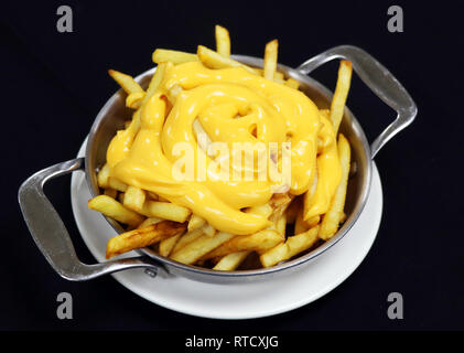 cheesy french fries on a metal plate with black background Stock Photo
