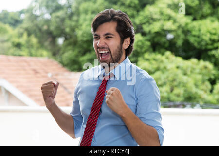 Successful cheering latin businessman with beard outdoors Stock Photo