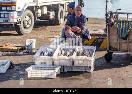 Fish vendor.  Fish are gutted and offered for sale on the quay side in not very clean fish boxes Stock Photo