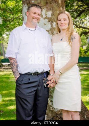 A young Caucasian couple poses for portraits after their wedding at Marshall Park in Ocean Springs, Mississippi. Stock Photo
