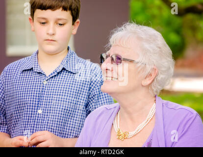 An older woman smiles as she sits with her grandson during a wedding at Marshall Park in Ocean Springs, Mississippi. Stock Photo