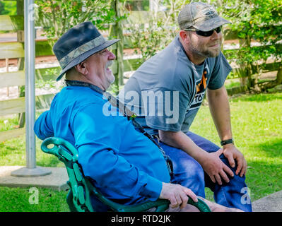 Two men smile as they watch a friend's wedding at Marshall Park in Ocean Springs, Mississippi. Stock Photo