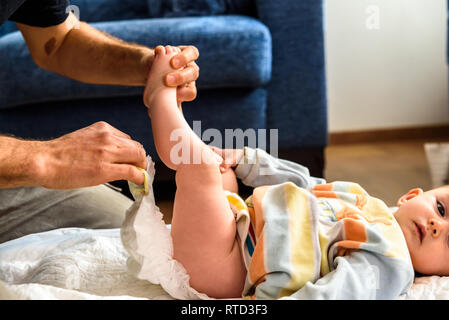 A father involved in taking care of his children by changing his daughter's dirty diaper. Concept of work family conciliation Stock Photo