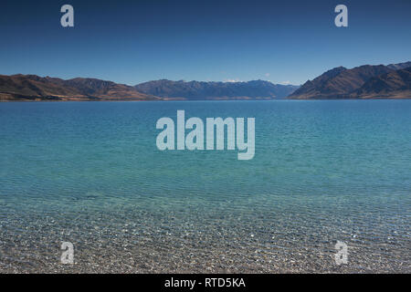 Beautiful Lake Hawea in summer blue sky clear water pebbles rocks clouds New Zealand South Island Stock Photo