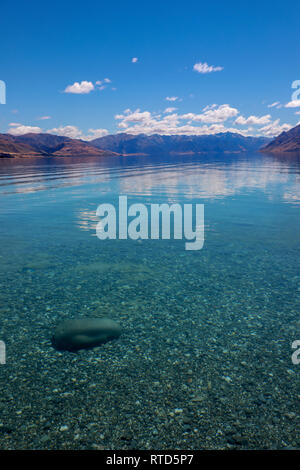 Beautiful Lake Hawea in summer blue sky clear water pebbles rocks clouds New Zealand South Island Stock Photo