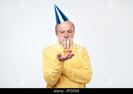 Human facial expressions. Sad father wearing cone hat and shirt looking at camera with grumpy expression, feeling tired Stock Photo