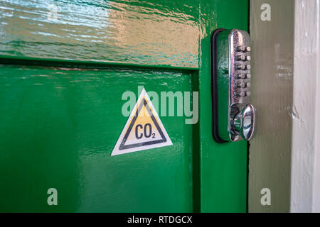 CO2 triangle warning sign and Digital Keypad Door Lock on an Old fashioned green wood door at Doncaster Station, England Stock Photo