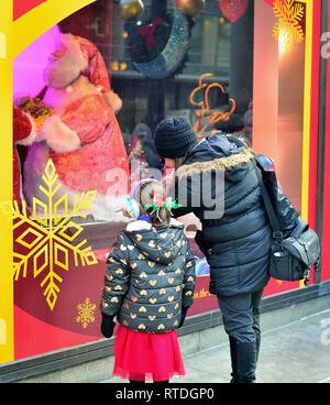 Chicago, Illinois, USA. A young girl, along with her mother gazes on a window at Macy's on State Street in Chicago decorated for Christmas. Stock Photo