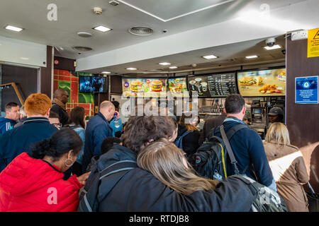 Large queue of people waiting to be served at McDonalds, Kings Cross, London, England Stock Photo