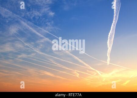 Code Strips in the sky over Schleswig at sunset in the early evening in late winter. In conspiracy theories, these thin clouds caused by airplanes are also referred to as chemtrails. Chemtrail is a portmanteau of the English chemical for chemicals and contrails for contrails, in German so about chemical strips. | usage worldwide Stock Photo