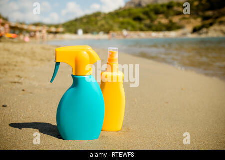 Sunscreen cream bottle on the sand beach.Composition with sun protection products.Sunblock or mosquito repellent bottle, spraying on body, sunbathing Stock Photo