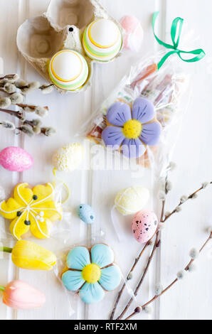 yellow tulips, ginger cookies, willow twigs, decorative eggs in a tray laid out on a white old wooden table, easter holiday background with sweets, fl Stock Photo