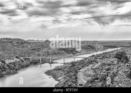 View downstream of the Vanderkloof Dam in the Orange River on the border of the Free State and Northern Cape Provinces. The single lane road bridge is Stock Photo