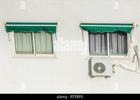 Two windows closed with roller shutters and air conditioning system installed on a hot summer day in Spain. Stock Photo