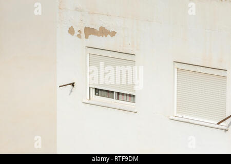 Two windows closed with roller shutters on a hot summer day in Spain. Isolated on white wall. Stock Photo