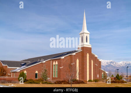 Church against snow capped mountain and cloudy sky. Snow capped mountain and vast blue sky with clouds can be seen in the background. Stock Photo