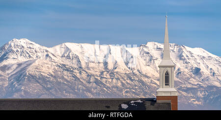 Church roof and steeple against Mount Timpanogos. The roof and steeple of a church in Eagle Mountain, Utah against Mount Timpanogos and blue sky. The  Stock Photo