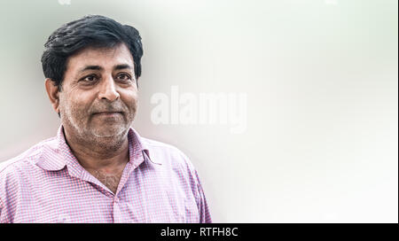 Portrait of a mature Indian Man giving expression of satisfaction with life. He is a typical Common Indian Man and common Father figure of South Asia Stock Photo