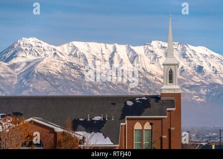 Mount Timpanogos behind a church in Eagle Mountain. Striking snow capped Mount Timpanogos against blue sky in Eagle Mountain, Utah. A church with stee Stock Photo