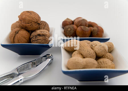 walnuts, hazelnuts and peanuts in three bowls on white background Stock Photo