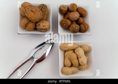 walnuts, hazelnuts and peanuts in three bowls on white background Stock Photo