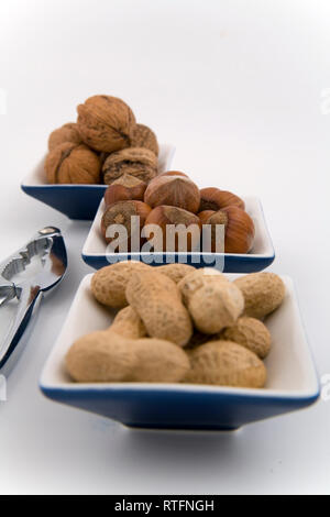 walnuts, hazelnuts and peanuts in three bowls on white background Stock Photo