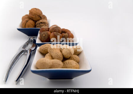 walnuts, hazelnuts and peanuts in three bowls on white background Stock Photo