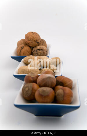 walnuts, hazelnuts and peanuts in three bowls on white background Stock Photo