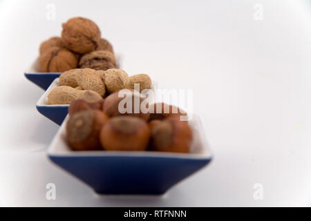walnuts, hazelnuts and peanuts in three bowls on white background Stock Photo