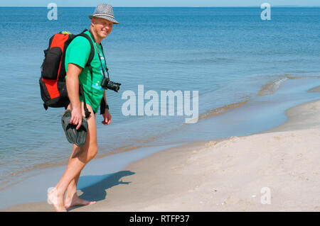 man walking on the beach, a tourist with a backpack walking on the sand, the Baltic sea, Kaliningrad region, Russia, August 9, 2018 Stock Photo