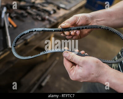 Old worn rubber alternator belt in men's hands. The concept of car