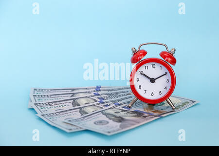 Red retro alarm clock and dollars on a blue background with free text space. Concept - time is money