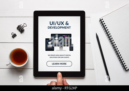 UI/UX design and development concept on tablet screen with office objects on white wooden table. All screen content is designed by me. Flat lay Stock Photo