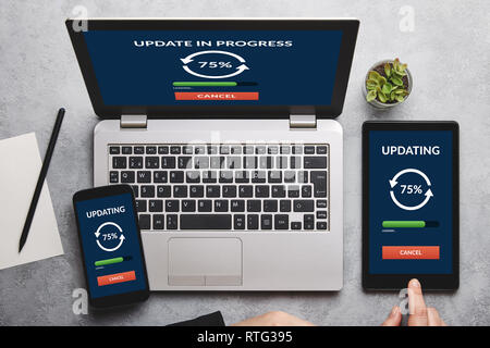 Update concept on laptop, tablet and smartphone screen over gray table. All screen content is designed by me. Flat lay Stock Photo