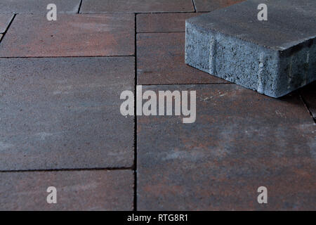 The paving stone of gray color lies on the pavement of brown color. Free space for text. Stock Photo