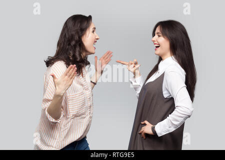Portrait of happy emotional beautiful best friends in casual style standing talking, discussing together. she pointing and telling unbelievable news a Stock Photo