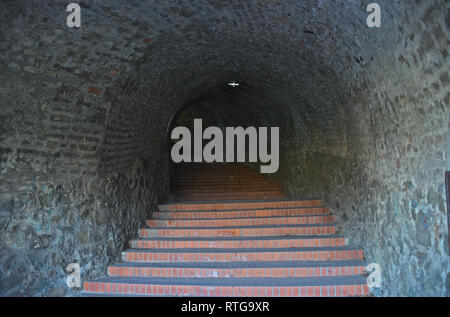 Long dark tunnel with red bricks stairs going up Stock Photo