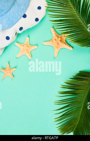 Summer female fashion outfit. Sunhat, polka dot towel, and starfish with tropical palm branches on blue background. Beach, vacation, travel concept, M Stock Photo