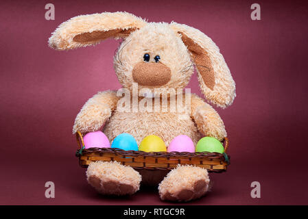 Stuffed soft rabbit with colorful bright painted eggs. Stock Photo