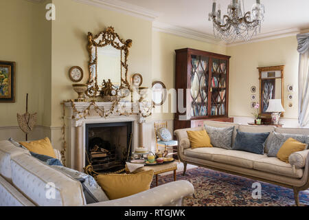 Oriental rug with regency style sofas and goldleaf garland on English fireplace Stock Photo