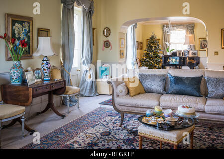 Christmas cake on tea tray in drawing room with view through to  artificial Christmas tree and grand piano bought at auction Stock Photo