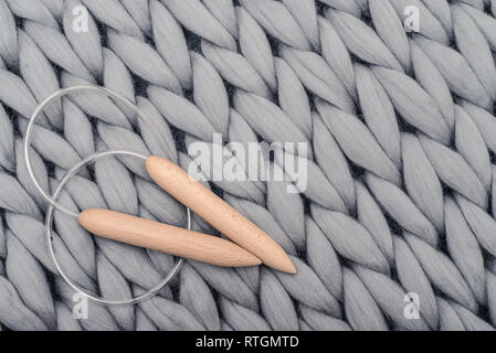 Knitting needles on gray knitted blanket from merino wool, super chunky yarn. Stock Photo