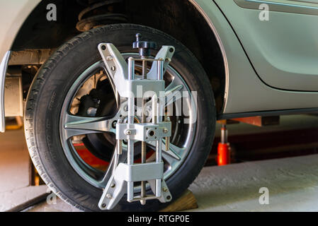 Car on stand with sensors on wheels for wheels alignment camber check in workshop of Service station. Stock Photo