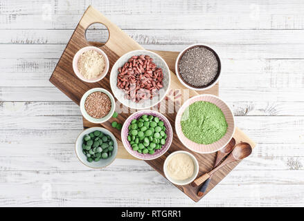 Different super foods in bowls on white wooden background, top view Stock Photo