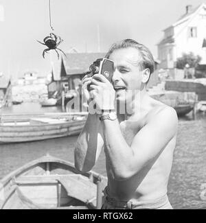Amateur filming in the 1940s. A man probably on his summer vaction is filming with his amateur camera what looks like a crab.   Photo Kristoffersson Stock Photo